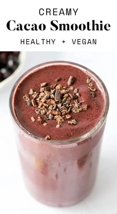 a smoothie in a glass with granola on top and text overlay that reads creamy cacao smoothie healthy + vega