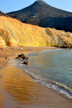 there is a mountain in the background and some water on the sand at the beach