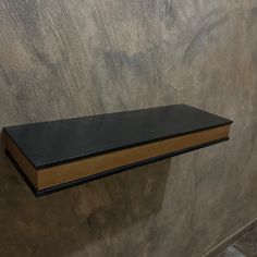 a book is sitting on top of a shelf in a room with concrete walls and flooring