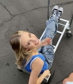 a young woman riding on top of a dolly with her legs spread out and smiling