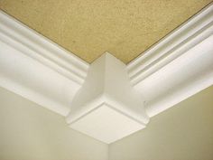 the corner of a room with white paint and molding on the ceiling is shown