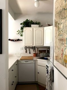 a map hangs on the wall in a kitchen with white cupboards and cabinets,