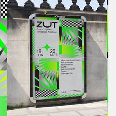 a large sign on the side of a building near a wall and fence with green, white and black designs