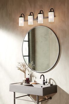 a bathroom sink with three lights above it