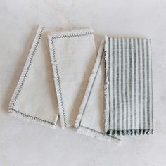 three pieces of cloth laid out on the floor next to each other with fringes