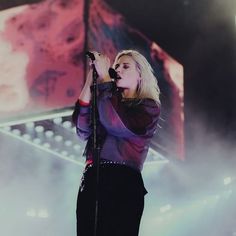 a woman standing on top of a stage holding a microphone in her hand and singing