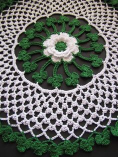 a crocheted doily with green and white flowers