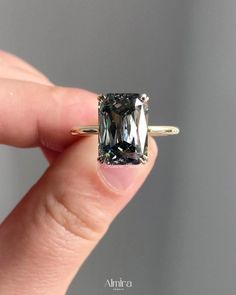 a person is holding an engagement ring with a large green diamond in it's center