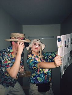 a man and woman standing next to each other while looking at the paper they are holding