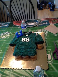 a cake shaped like a football jersey sitting on top of a green tablecloth covered table