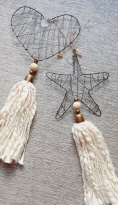 two white tasseled earrings sitting on top of a gray cloth covered tablecloth