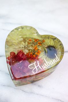 a glass heart shaped box with flowers and the word husband written on it in white lettering