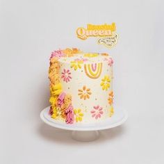 a white cake with yellow and pink frosting on a plate next to a happy birthday sign