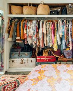 an organized closet with clothes, shoes and suitcases on the shelves in front of it