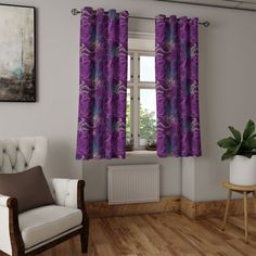 a living room filled with furniture and a window covered in purple curtaines next to a chair