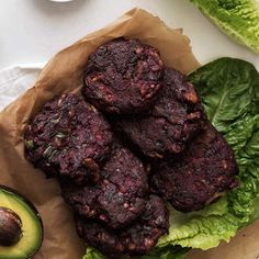 some meat patties are on top of lettuce and an avocado