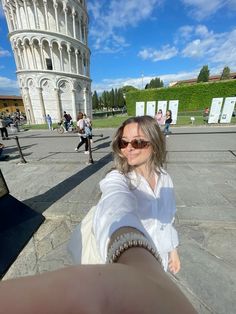 a woman taking a selfie in front of the leaning tower