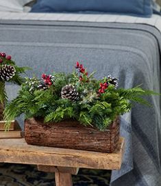 two wooden planters with pine cones and greenery in them on a small table