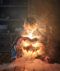 a young boy holding a glowing pumpkin in his hands