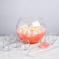 a bowl filled with water and lemons on top of a table next to glasses