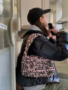 a woman sitting on a bench holding a cell phone and wearing a black baseball cap