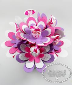 a bouquet of paper flowers on a white table with pink and purple petals in the center