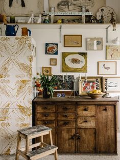 a wooden dresser sitting next to a wall covered in pictures