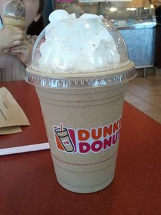 a dunkin'donuts drink sitting on top of a table next to a woman