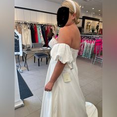 a woman in a white wedding dress looking at dresses on hangers inside a clothing store