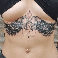 a woman's stomach with an intricate tattoo design on the side and large wings