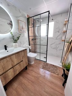 a bathroom with wood flooring and white walls, along with a large mirror on the wall