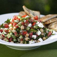 a white plate topped with a salad and pita bread on top of a table