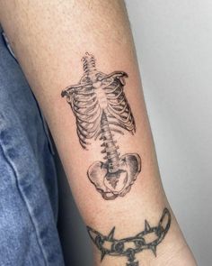 a man's arm with a tattoo on it that has a skeleton and barbed wire