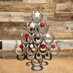 a christmas tree made out of horseshoes and balls on a wooden surface with wood planks in the background