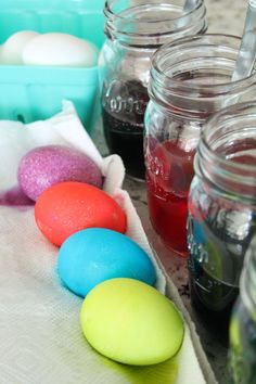 several jars filled with colored eggs sitting on top of a table