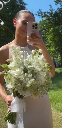 a woman taking a selfie with her cell phone while holding a bouquet of flowers