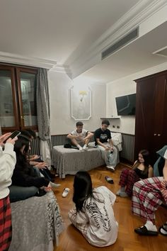 group of people sitting on the floor in a living room with one person taking a photo