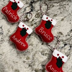 three red and white christmas stocking ornaments hanging on a granite counter with the words branche andyew written on them