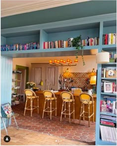 a living room filled with lots of furniture and bookshelves next to a kitchen