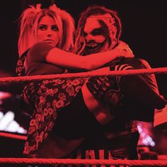 two women hugging each other while standing on a rope in the middle of a wrestling ring