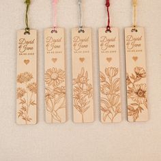 four wooden bookmarks with flowers and hearts hanging from the strings on a white surface