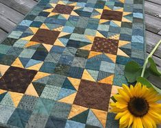 a sunflower sitting on top of a wooden deck next to a quilted table runner