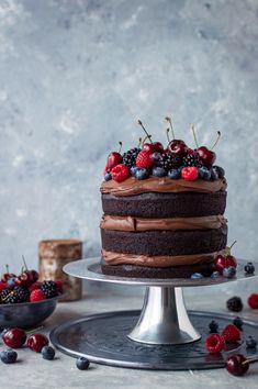 a cake with chocolate frosting and fresh berries on top is sitting on a platter