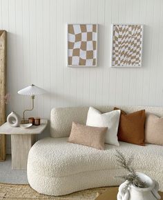 a living room with white couches and pillows on top of the couch, next to a coffee table