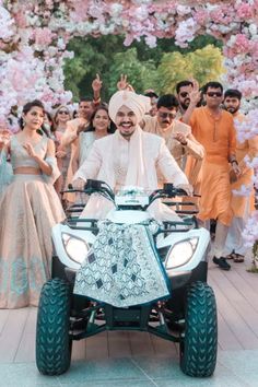 a man riding on the back of a four - wheeler in front of a group of people