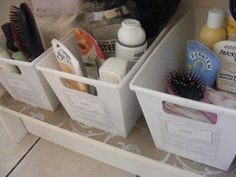 three bins with hair brushes, lotion and other personal care items in them