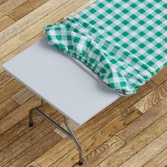 a green and white checkered table cloth on top of a small metal folding table