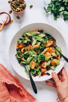 a white bowl filled with oranges and broccoli on top of a table