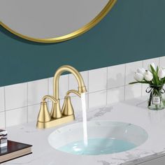 a bathroom sink with a gold faucet and marble counter top next to a round mirror