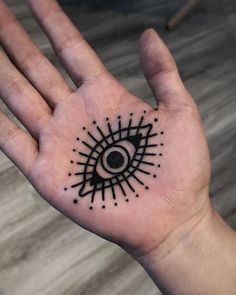 a person's hand with a black and white tattoo design on the middle of it